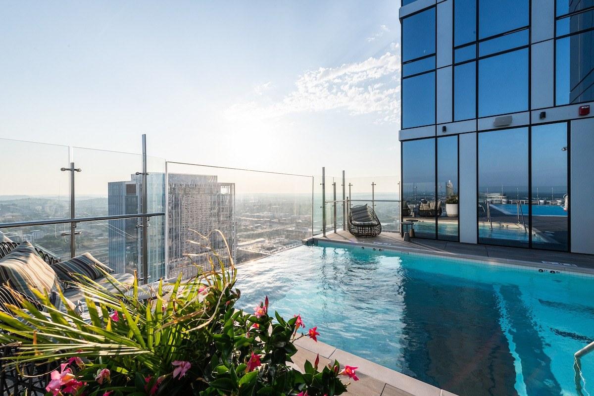 A rooftop pool on a condominium tower, the skyline behind it at sunrise